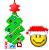 Green Christmas tree with red star, multicolored ornaments, and candy cane base next to smiling yellow face wearing red Santa hat on gray background.