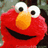 Red puppet with large white eyes and orange nose on blue background with pixelated text "Tickle Me!".