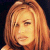 Pixelated static image of a person with long light brown hair against dark background, rendered in warm orange and yellow tones.