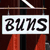 A pixelated sign with bold black text reading "BUMS" on a white background, suspended by thin lines against a dark backdrop with red vertical elements below.