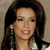 Pixelated close-up of a person with long dark hair, wearing a white top and dark dangling earrings, against a neutral background.