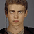 Static pixelated image of a young man with brown hair and light skin wearing a dark jacket over a light shirt against a gray background.