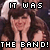 Pixelated static image of a person with long dark hair wearing a sleeveless top, overlaid with bold pixelated text reading "IT WAS THE BAND!" in black and white.