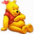 Yellow bear with red shirt and pink flower on head sits with arms crossed, legs extended, and smiling expression.