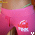 A person wearing pink high-waisted shorts with 'LOVE PINK' text and a logo, showing midsection and waistband.
