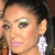 A woman with dark hair pulled back, wearing large white earrings and green eyeshadow, shown in four with slight variations in head position and background