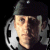 Static pixelated icon of a person wearing a dark cap and light-colored shirt with a film reel prop, set against black background.