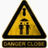 Yellow triangular warning sign with black border and stylized 'T' symbol, positioned above a brown rectangular bar with pixelated text.