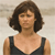 A pixelated image of a person with short brown hair wearing a black sleeveless top against a light background.