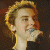 A pixelated image showing a person singing into a microphone on the left and green text reading "Original Icons .com" on the right against a dark background.
