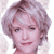 Static pixelated image of a person with light brown curly hair and blue eyes, wearing a red top against a white background.