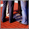 Two side-by-side show legs in dark and light pants on a red-tiled floor with shadows; the right has a white star symbol at bottom center