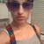 Pixelated image of a person wearing dark sunglasses and a sleeveless top with multicolored straps, set against a blurred background.