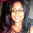 Pixelated static image of a person with light skin tone, dark hair, and glasses smiling against a blurred background.
