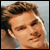 Static pixelated close-up of a person's face with brown hair and light skin tone, cropped to show forehead through chin against a gray background.