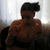 Pixelated image of a shirtless person with dark hair wearing black pants, seated against a light background.