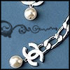 Two silver-toned jewelry pieces with pearl accents on a blue background featuring dark scrollwork.