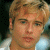 A pixelated image of a person with light brown hair and fair skin, wearing a white shirt against a dark background.