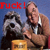 A man in a brown cardigan and white shirt holds a dog's paw over a yellow bucket labeled 'SPROG' with red text reading 'Fuck!' on the left and 'Ass!' on the right.