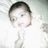 A baby in a white onesie lies on a light-colored surface with faint patterns, showing subtle variations across three views.