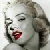 Pixelated grayscale portrait of a woman with closed eyes, red lips, and dark hair styled in waves, cropped to show upper face and shoulder.