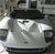 Pixelated static image of a silver vehicle with black accents, viewed from a low angle against a blurred background.