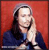 A pixelated portrait of a person with long dark hair wearing a dark blue top against a solid red background, hands clasped near the face.
