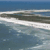 A static pixelated image of a coastal scene with layered horizontal bands of blue, white, and gray tones depicting water and sky.