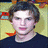 Pixelated static image of a person with dark hair wearing a dark shirt against a yellowish background with red and blue elements.