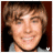 Pixelated portrait of a smiling person with light brown hair, wearing a gray top against dark background.