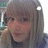 Pixelated static image of a person with light brown hair and bangs, wearing dark clothing against a blurred background.