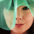 Pixelated close-up of a person's face with light skin, brown hair, and red lips against a green and white background.