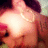 A pixelated close-up of a person's upper body with blurred facial features, wearing dark hair and red clothing against a muted background.