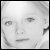 Grayscale pixelated portrait of a person with short hair, neutral expression, and visible facial features including eyes, nose, and mouth.