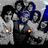 Pixelated image of two figures in formal attire holding hands, with glowing orange lights and blue accents against a gray background.
