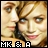 Pixelated image of a person with light brown hair and green eyes, wearing dark clothing, with text "MK & A" at the bottom.