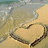 A beach scene with a heart drawn in sand, waves lapping at the shore, and text overlays reading 'Summer 08' and 'Friends, horses, beach bonfires, winning on much more.'