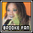Pixelated square image of a person with long dark hair holding a microphone against an orange background, with text reading BROOKE FAN at the bottom.