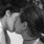 Two people in a close embrace, one with dark hair and the other with lighter hair, sharing an intimate moment. The left side is grayscale while the right side has color.