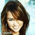 Pixelated close-up of a person with long brown hair against light blue background, static image.