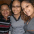 Three people pose together in a group photo with two wearing gray V-neck shirts and one in striped shirt, all smiling.
