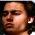 Pixelated close-up of a person's face with closed eyes, showing skin tones and dark hair against a dark background.
