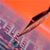 A pixelated image shows a diagonal object with a dark top and light brown body against a gradient background of orange and purple hues.