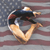 Pixelated static image of a gymnast performing a handstand on a balance beam with an American flag background.