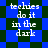 Pixelated text 'techies do it in the dark' repeated on a blue and green checkered background with shifting diamond patterns.