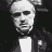 Pixelated grayscale image of a man with short hair, wearing a dark suit and white shirt against a black background.
