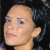 Pixelated close-up of a person's face with light skin tone, dark hair, and visible ear against dark background.