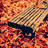 A pixelated image with a central dark shape against an orange and red gradient background, featuring a checkered pattern overlay on the upper portion.