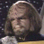 Pixelated static image of a person with light brown hair and neutral expression against dark background, likely from Star Trek: The Next Generation media.