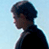 Pixelated static image of a person's profile with dark hair and black clothing against a light blue background, rendered in low-resolution 256x256 pixels.